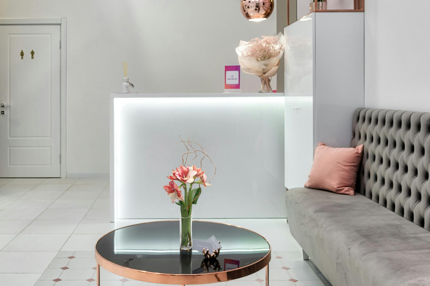 Modern interior with a gray sofa, round coffee table, and decorative flowers.